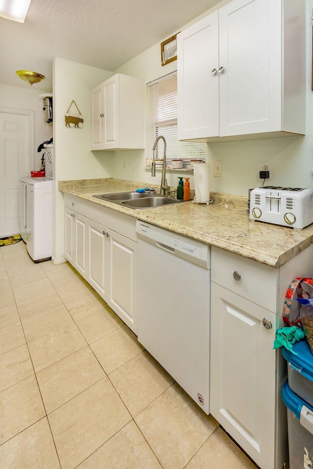 kitchen featuring white dishwasher, a sink, washer and dryer, and white cabinets