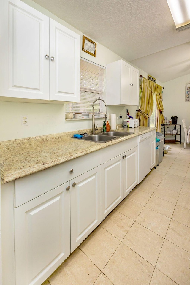 kitchen featuring light tile patterned flooring, white dishwasher, a sink, and white cabinetry