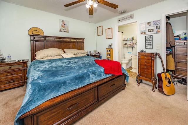 bedroom with visible vents, ensuite bathroom, a ceiling fan, and light colored carpet