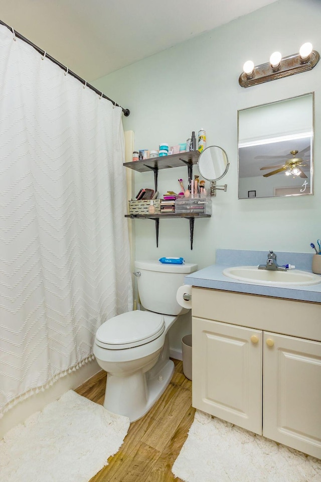 bathroom with ceiling fan, toilet, a shower with shower curtain, wood finished floors, and vanity