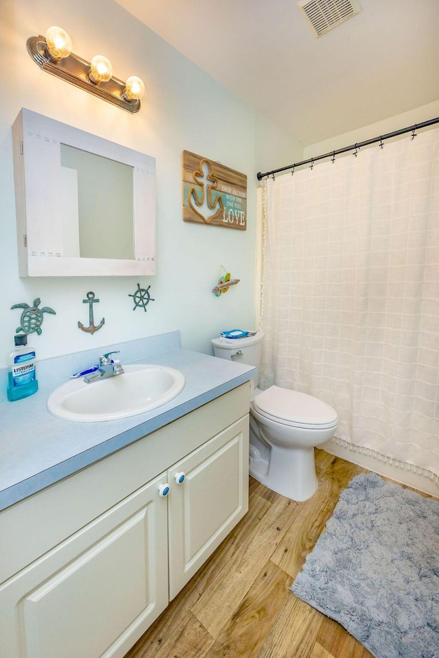 full bathroom with visible vents, toilet, vanity, wood finished floors, and a shower with curtain