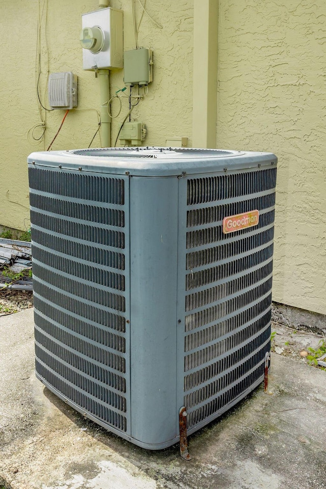 details with cooling unit, electric meter, and stucco siding