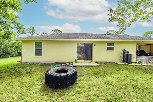 rear view of house featuring a patio area, a lawn, a fire pit, and stucco siding