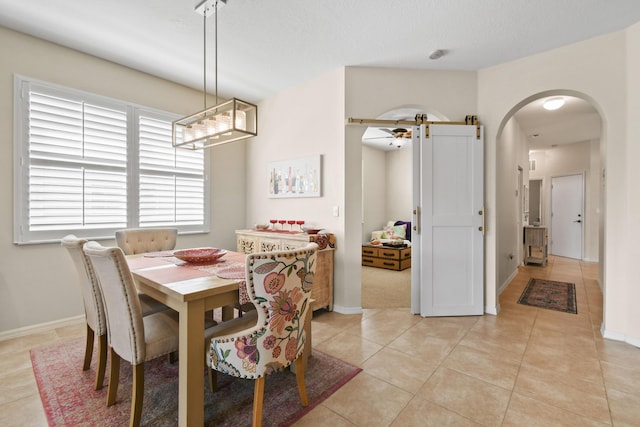 dining room with arched walkways, light tile patterned flooring, and baseboards