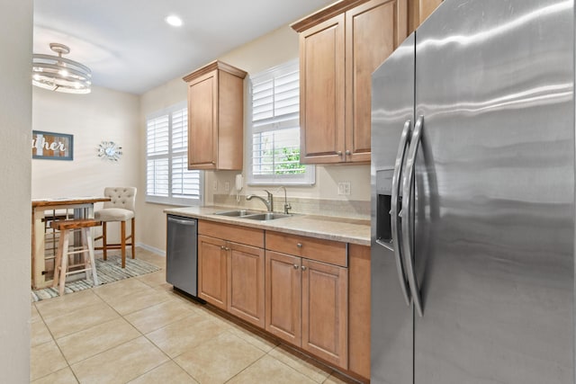 kitchen with decorative light fixtures, appliances with stainless steel finishes, light tile patterned flooring, a sink, and baseboards