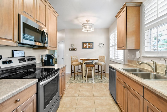 kitchen featuring light countertops, appliances with stainless steel finishes, light tile patterned flooring, and a sink