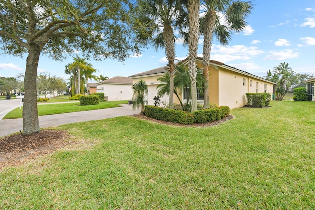 view of side of home with decorative driveway, a yard, an attached garage, and stucco siding