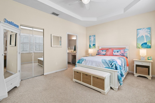 bedroom featuring connected bathroom, carpet flooring, visible vents, baseboards, and a raised ceiling