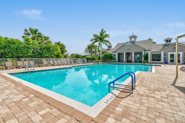 pool with a patio area and fence