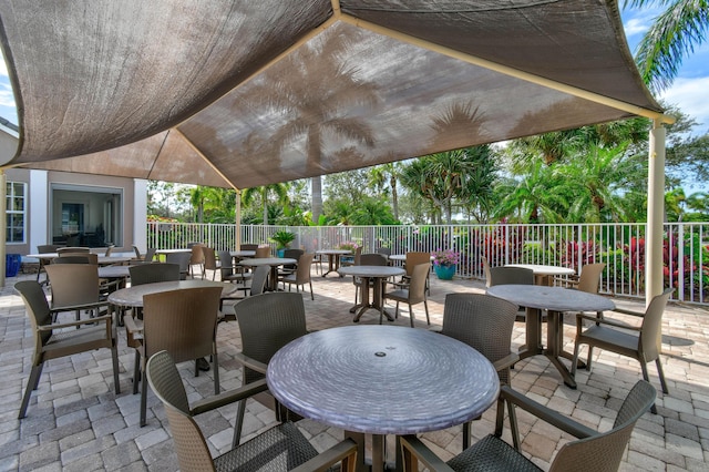 view of patio featuring a fireplace, fence, and outdoor dining space