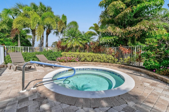 view of swimming pool with a patio area, fence, and an in ground hot tub