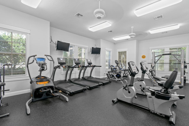 gym with a textured ceiling, visible vents, and baseboards