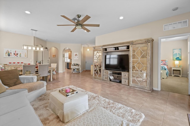 living area with light tile patterned floors, visible vents, arched walkways, a ceiling fan, and recessed lighting