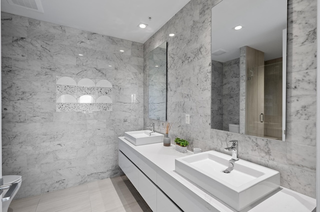 full bath with toilet, a sink, double vanity, and tile walls