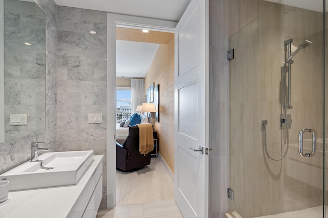 bathroom featuring a stall shower, connected bathroom, vanity, and tile walls