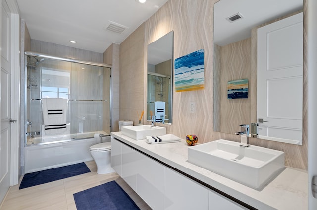 full bathroom with combined bath / shower with glass door, a sink, visible vents, and toilet