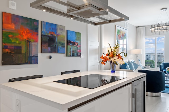 kitchen with black electric cooktop, white cabinets, open floor plan, light countertops, and decorative light fixtures