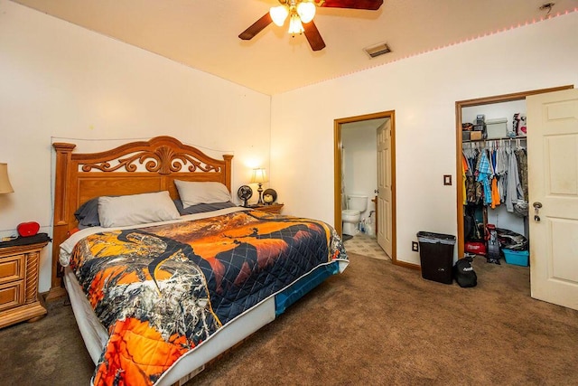 bedroom with dark colored carpet, a closet, visible vents, a spacious closet, and ensuite bathroom