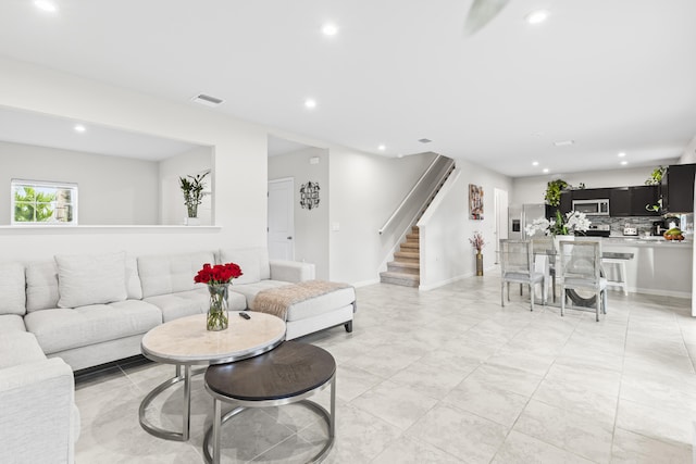 living room featuring baseboards, stairs, visible vents, and recessed lighting