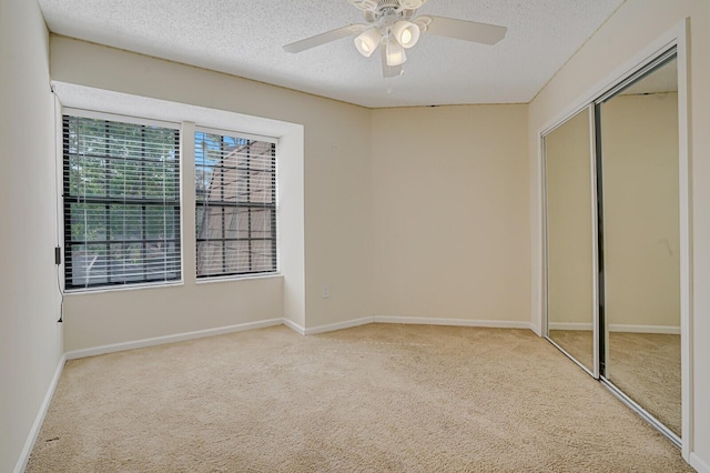 unfurnished bedroom featuring baseboards, ceiling fan, a textured ceiling, carpet floors, and a closet