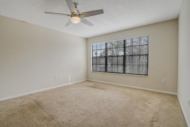 carpeted empty room with a textured ceiling, ceiling fan, and baseboards