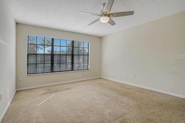 carpeted spare room featuring a ceiling fan, a textured ceiling, and baseboards