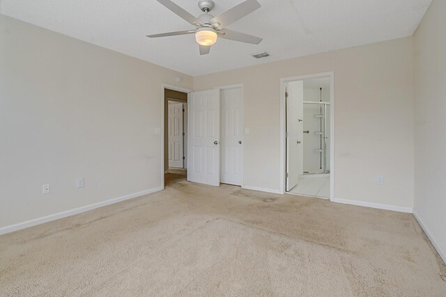 unfurnished bedroom with baseboards, ensuite bath, visible vents, and light colored carpet