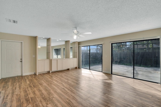 unfurnished room with baseboards, visible vents, light wood-style flooring, ceiling fan, and a textured ceiling