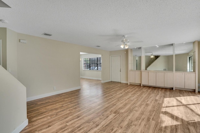 empty room with light wood-style flooring, baseboards, and a textured ceiling