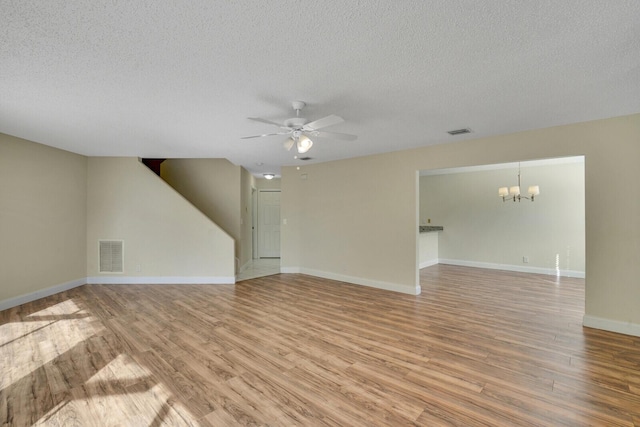 unfurnished living room with visible vents, light wood-style flooring, baseboards, and ceiling fan with notable chandelier