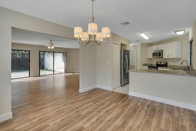 kitchen with stainless steel appliances, visible vents, white cabinets, open floor plan, and hanging light fixtures