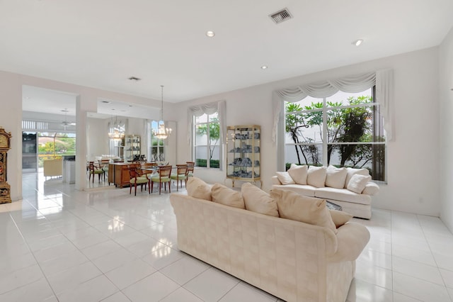 living area featuring light tile patterned floors, recessed lighting, visible vents, and a notable chandelier