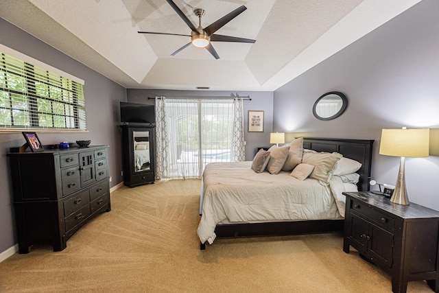 bedroom with a tray ceiling, multiple windows, light colored carpet, and access to exterior