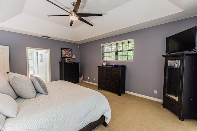 bedroom with light carpet, baseboards, visible vents, a raised ceiling, and ceiling fan