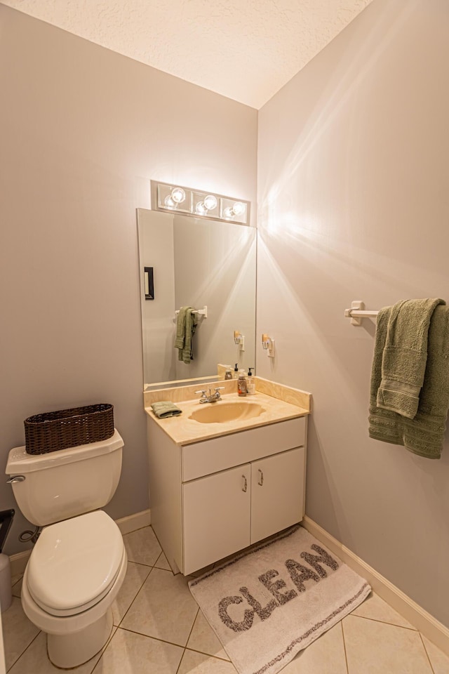 bathroom featuring baseboards, vanity, toilet, and tile patterned floors