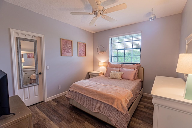 bedroom featuring ceiling fan, a textured ceiling, dark wood finished floors, and baseboards