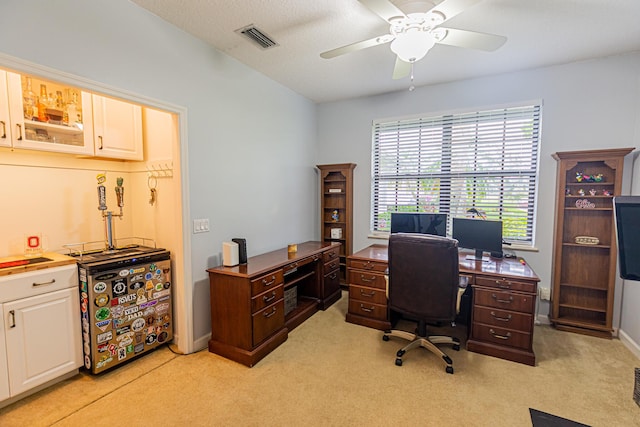 office with baseboards, visible vents, a ceiling fan, and light colored carpet