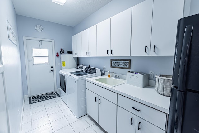 clothes washing area featuring cabinet space, light tile patterned floors, electric water heater, washer and dryer, and a sink