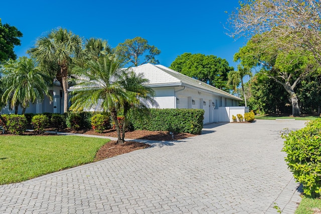 view of front of home featuring a garage, a front lawn, decorative driveway, and stucco siding