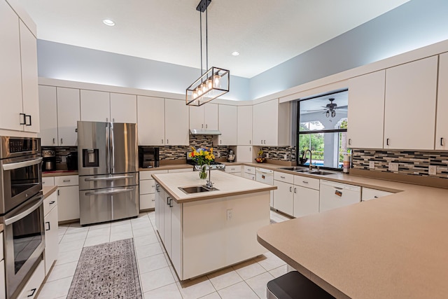 kitchen featuring appliances with stainless steel finishes, decorative light fixtures, a sink, and tasteful backsplash