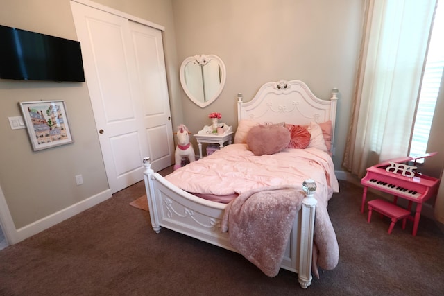 bedroom with a closet, dark carpet, and baseboards