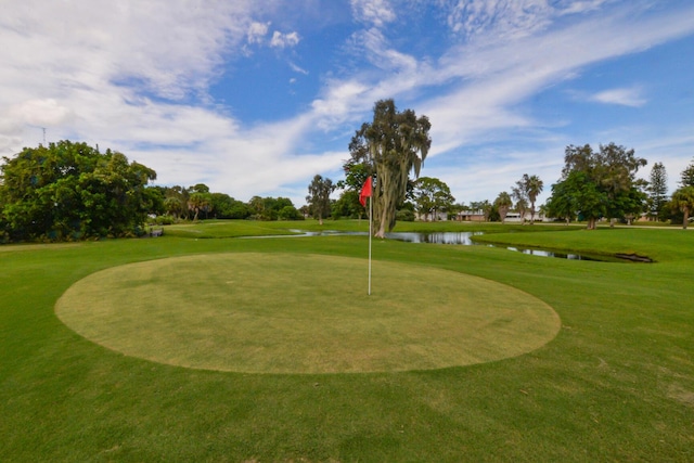 surrounding community featuring a water view, view of golf course, and a lawn