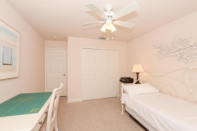 bedroom with light carpet, a ceiling fan, visible vents, and a closet