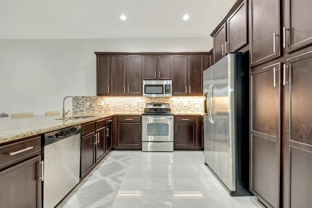 kitchen with appliances with stainless steel finishes, dark brown cabinetry, a sink, and decorative backsplash