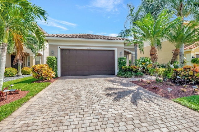 mediterranean / spanish-style house featuring a garage, decorative driveway, a tiled roof, and stucco siding