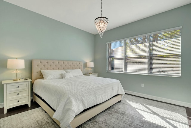 bedroom featuring baseboards, dark wood finished floors, and a notable chandelier