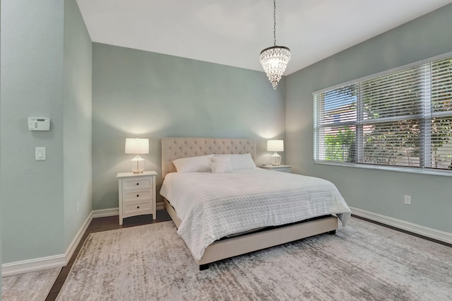 bedroom with a chandelier, wood finished floors, and baseboards