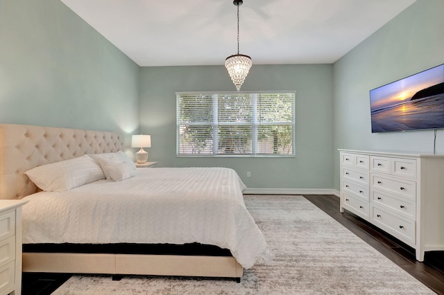 bedroom featuring a notable chandelier, dark wood-type flooring, and baseboards