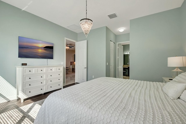 bedroom with dark wood-type flooring, visible vents, and an inviting chandelier