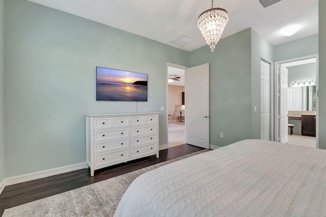 bedroom with a notable chandelier, dark wood finished floors, ensuite bath, and baseboards